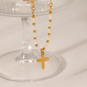 Detailed close-up of Baroque pearls and a gold-plated cross pendant on a chic necklace