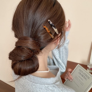 Dettaglio di fermagli in acrilico tartarugato e marmorizzato su un'acconciatura a chignon