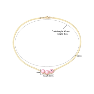 Détail des perles émaillées œil rose sur une chaîne serpent dorée de 2,5 mm de large