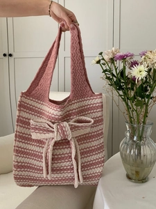 Detail of pink and white knitted tote bag featuring a large decorative bow and wave pattern