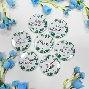 Close-up of Team Bride tinplate badges with floral wreath design for bridal party