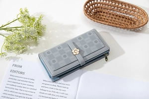 Detail of greyish blue wallet featuring floral metal clasp and daisy embossed pattern
