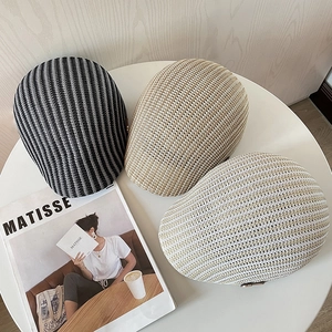 Berretti intrecciati traspiranti a righe, kaki e beige su un tavolo in stile moderno