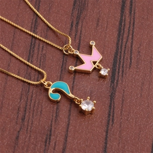 Detail of gold-plated necklaces featuring pink crown and blue question mark pendants