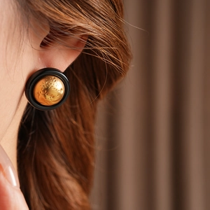 Macro shot of vintage round earrings with black matte rim and gold hammered texture