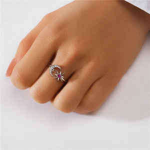 Macro shot of silver crescent moon and star ring with purple gemstone and crystals