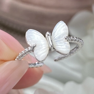 Detailed view of an open silver ring featuring a white mother-of-pearl butterfly charm