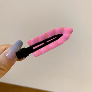 Close-up of pink wavy textured hair clip with black metal base held by hand