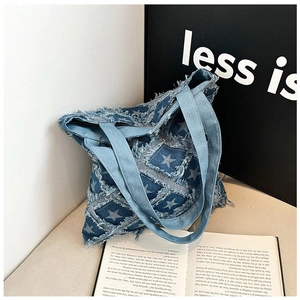 Detail of vintage denim tote bag featuring star patch embroidery and frayed edge trim
