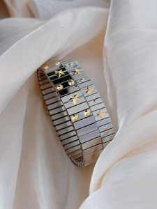 Detail of silver stainless steel stretch bracelet featuring golden star and stud accents
