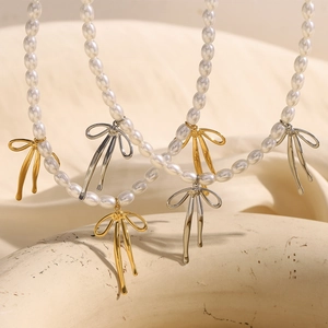Gros plan d'un collier de perles avec des pendentifs en forme de nœud dorés et argentés