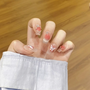 Detail von Blush-Kunstnägeln mit 3D-Schleifen, Perlen und Diamanten an einer Hand