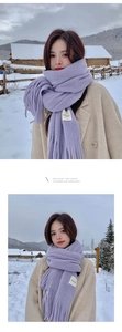 Detail of lavender knit scarf with handmade label and long tassels on a winter coat