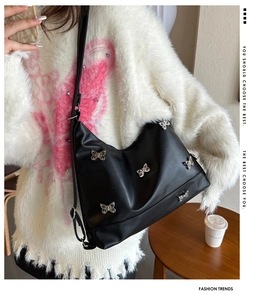 Modische schwarze Halbmond-Schultertasche mit silbernen Schmetterlingen am Model