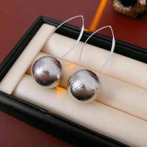 Détail de boucles d'oreilles sphériques argentées avec surface texturée sur cuir rouge