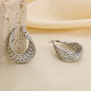 Gros plan de boucles d'oreilles argentées en U avec texture tressée sur fond satiné