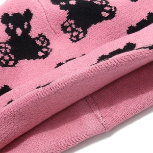 Detailed close-up of pink knit beanie with black bear pattern and high-quality texture
