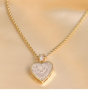 Macro shot of gold hip hop heart pendant with zircon inlay on luxury silk background