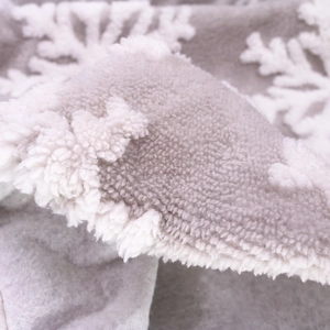Macro shot of white plush snowflake embroidery on a soft gray faux fur Christmas tree skirt