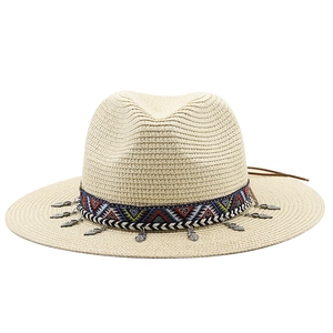 Détail d'un chapeau de paille beige avec bande ethnique et breloques en argent