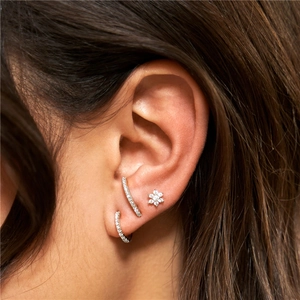 Close-up of silver flower and curved crystal stud earrings set worn by a model