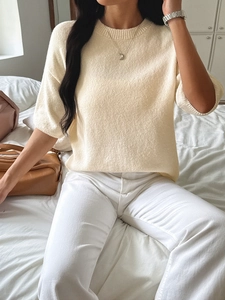 Detail of a beige knitted sweater featuring a textured pattern and comfortable fit