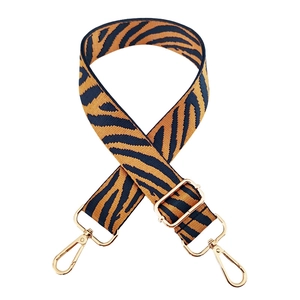 Detail of adjustable zebra print bag strap in orange and black with golden lobster hooks
