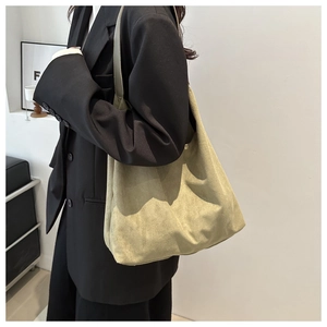Detailed view of a khaki matte suede tote bag styled with a professional black blazer