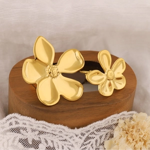 Detail view of gold flower earrings on a wooden base with white lace and dried flowers