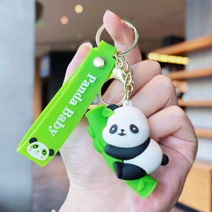 Detail of cute 3D panda keychain with green silicone strap and golden metal clasp