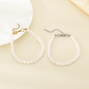 Elegant set of two pearl bracelets with gold and silver alloy clasps on silk background