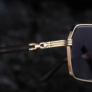 Macro detail of golden metal hinge and premium dark lens on vintage square sunglasses