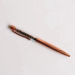 Close-up of rose gold crystal ballpoint pen with colorful gemstones in clear barrel