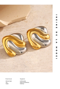 Close-up of wavy irregular two-tone stud earrings with gold and silver metallic finish