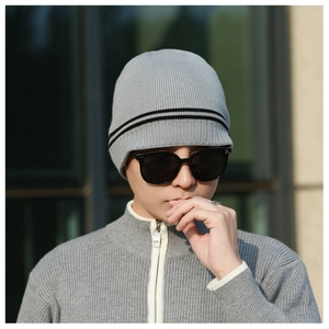 Detail of grey knitted beanie with black stripes and small brim for winter warmth