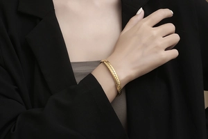 Detalle de una pulsera dorada de acero inoxidable con un diseño de textura de espiga