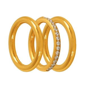 Three-piece gold metal stacking rings set with sparkling clear zircons on white background