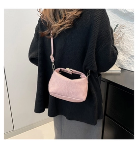 Suede-textured pink crossbody bag worn over a black sweater for a retro casual look