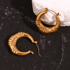 Detail of 18K gold plated hollow ribbed hoop earrings on natural stone textures