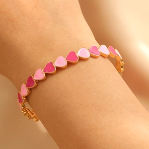 Dettaglio del bracciale in smalto sfumato cuore rosa al polso con placcatura oro