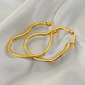 Boucles d'oreilles cœur en acier inoxydable doré sur fond de tissu de soie blanc