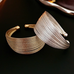 Macro shot of multi-layer woven metal open bracelets in polished gold and silver finishes