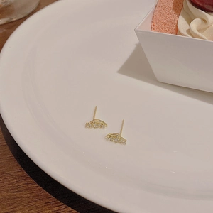 Orecchini a perno in argento S925 dorato con micro zirconi su un piatto di porcellana