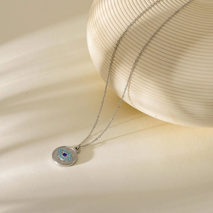 Close-up of a silver Evil Eye coin pendant necklace with sparkling blue rhinestones
