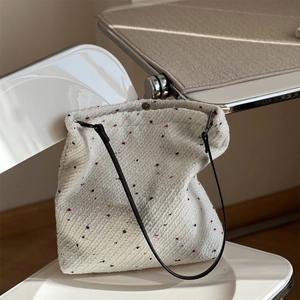 Detail of white tweed tote bag with colorful specks and black straps on a chair