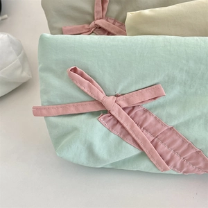 Dettaglio di astuccio in cotone verde menta con fiocco decorativo in nastro rosa