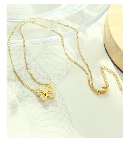 Detail of gold butterfly necklace with clear zircon stones on a white textured background