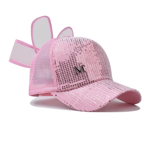 Vue détaillée de la casquette rose à paillettes avec nœud en maille et lettre M argent