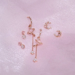 Detail of 18K rose gold star and moon earrings with pink gems on silk fabric