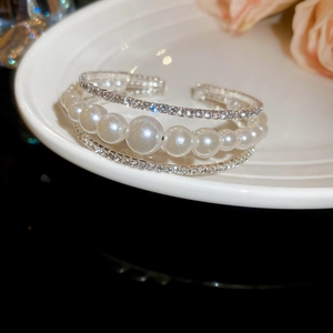 Detail of multi-layer pearl and crystal open bracelet on an elegant white ceramic tray